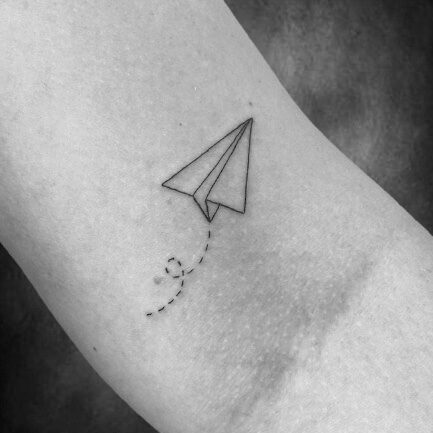 Kleines minimalistisches Papierflieger-Tattoo mit gepunkteter Flugbahn, gestochen im Black Dot Tattoo Studio Besigheim.